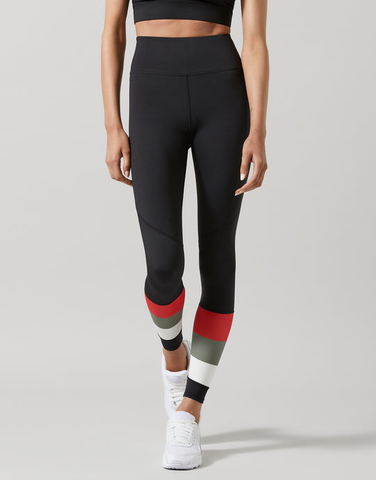Person wearing black leggings with red and gray accents on a light gray background