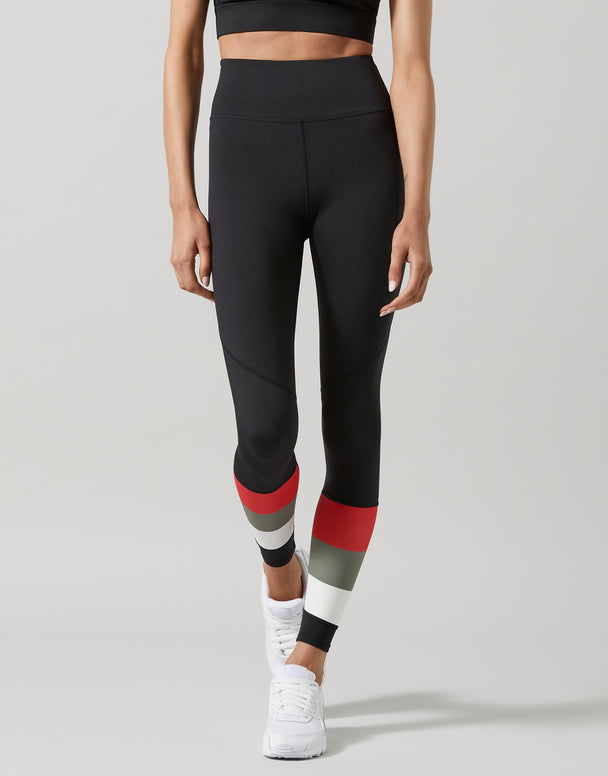 Person wearing black leggings with red and gray accents on a light gray background