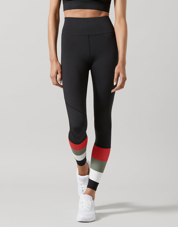 Person wearing black leggings with red and gray accents on a light gray background