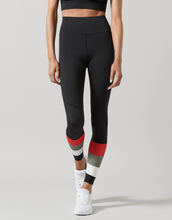 Person wearing black leggings with red and gray accents on a light gray background
