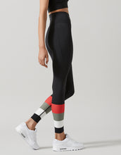 Person wearing black leggings with colorful panels on a gray background