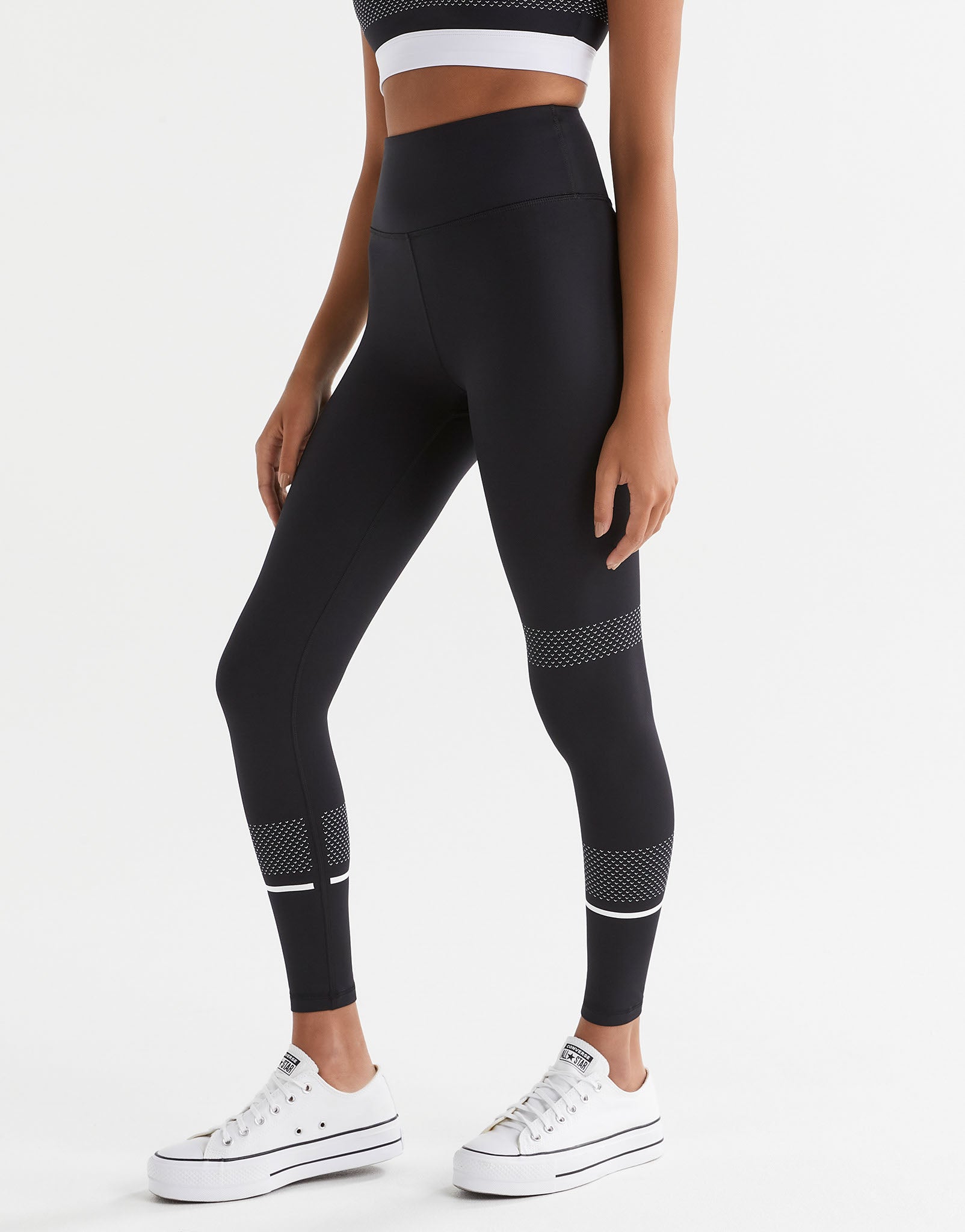 Person wearing black leggings with white accents on a light gray background