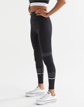 Person wearing black leggings with white accents on a white background