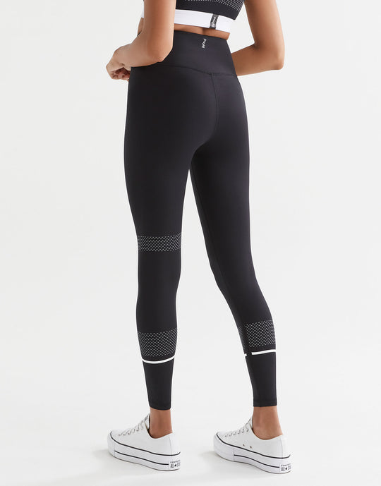 Person wearing black leggings with white accents on a white background