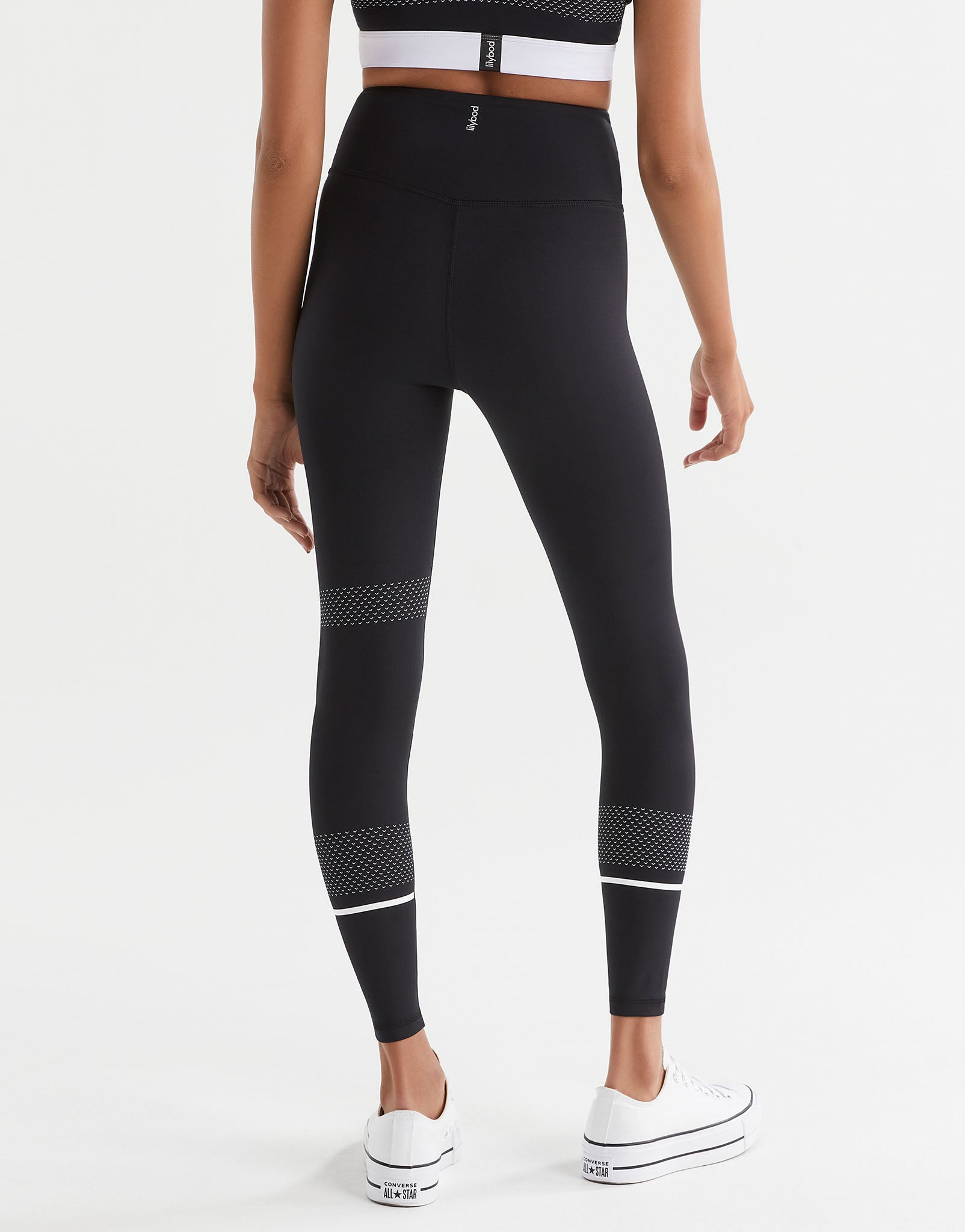 Person wearing black leggings with white accents on a white background