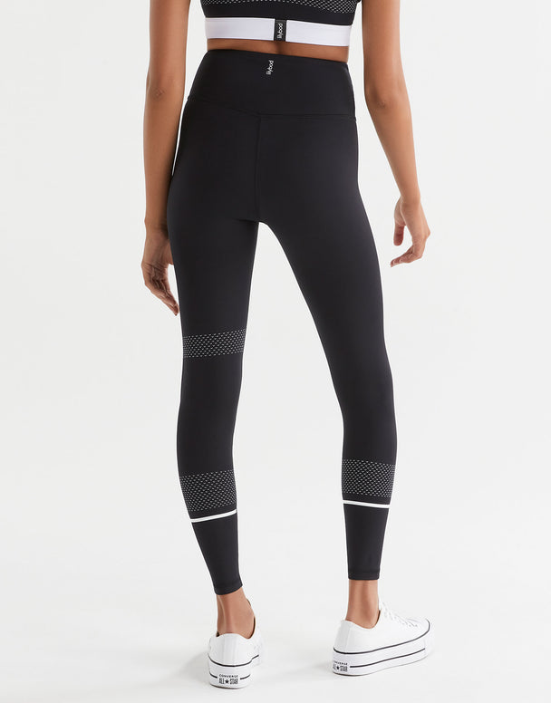 Person wearing black leggings with white accents on a white background