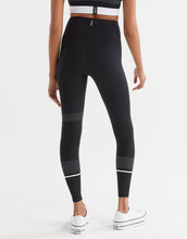 Person wearing black leggings with white accents on a white background
