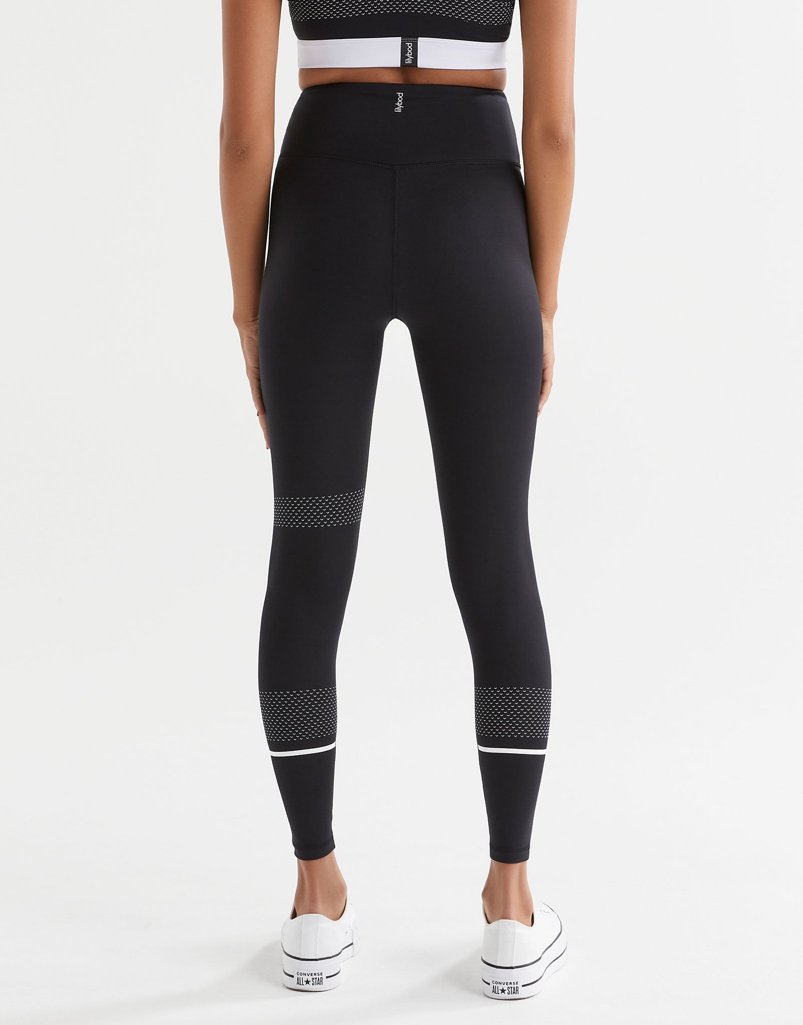 A pair of high-waisted full length leggings in black with white contrast stripes and mesh details. The brand logo 'Lilybod' is visible at the center.
