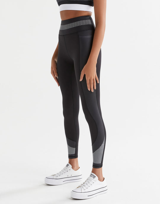 Woman wearing black activewear leggings and white sneakers.