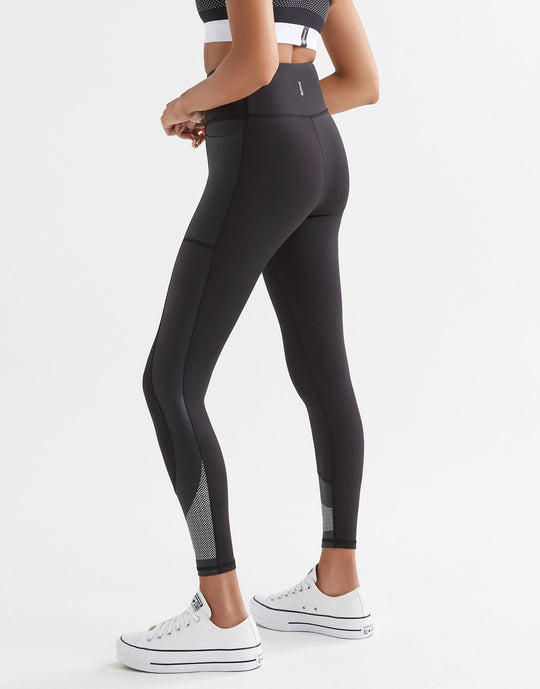 Woman wearing black sporty leggings with pockets and white sneakers.