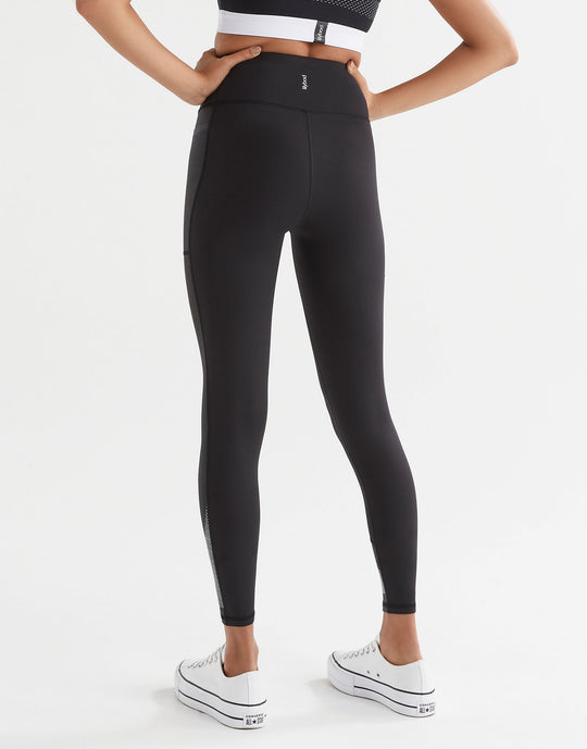 Woman wearing black sporty leggings and white sneakers. Rear view.