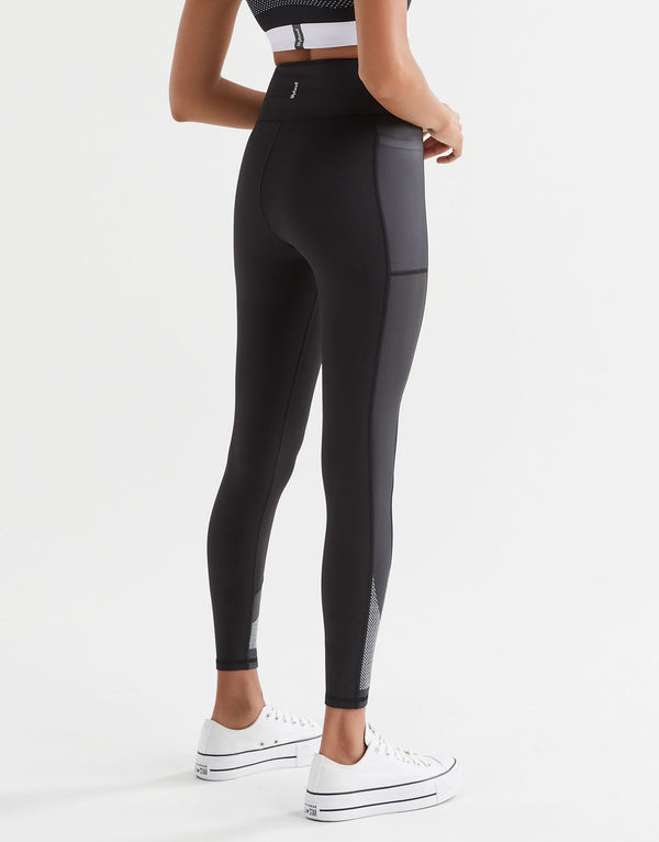 Woman wearing black sporty leggings, sports bra and white sneakers.