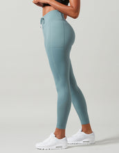 Person wearing teal leggings with a plain background