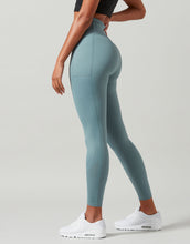 Woman wearing teal leggings and white sneakers on a plain background