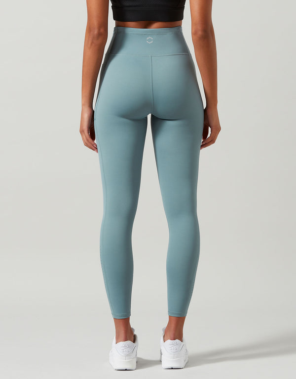 Woman wearing green gym leggings on a grey background