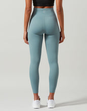 Woman wearing green gym leggings on a grey background