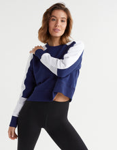 Woman wearing a blue and white striped sweater with black leggings on a white background