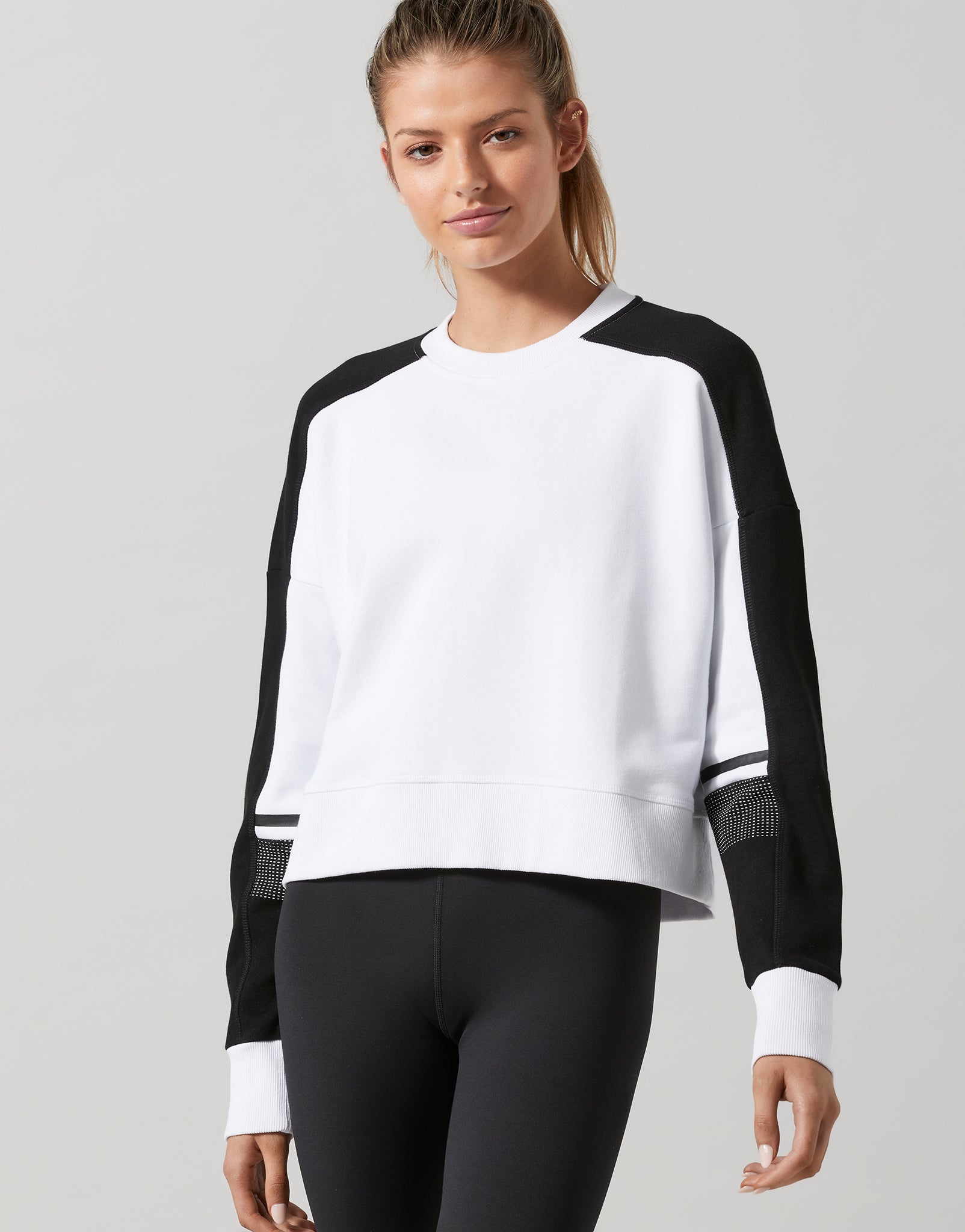 Woman wearing a black and white long-sleeve top with a plain background