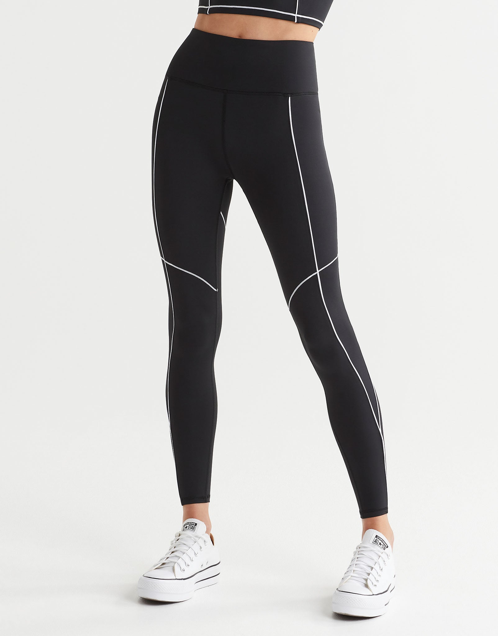 A woman wearing black leggings and white runners.