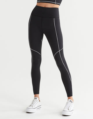 A woman wearing black leggings and white runners.