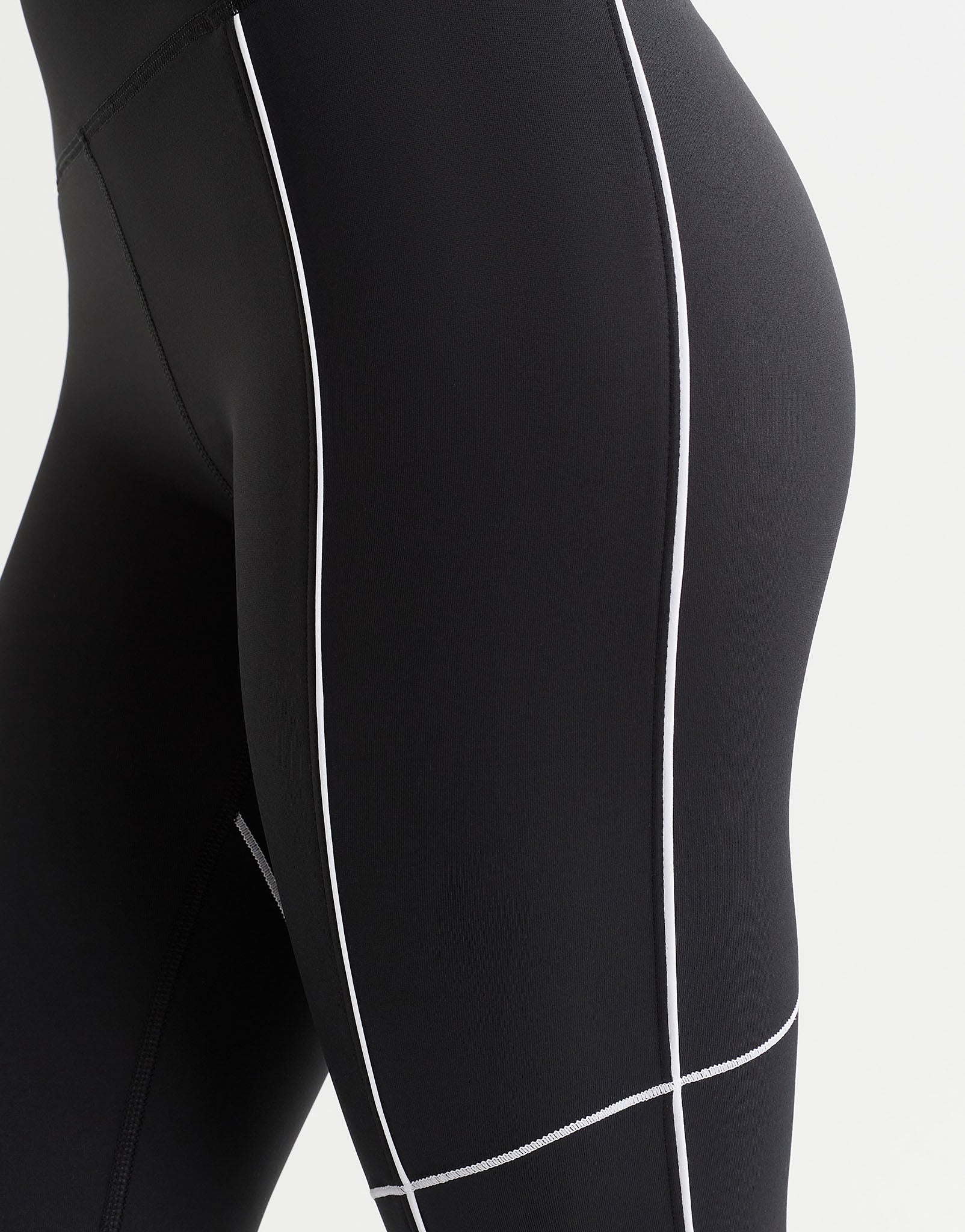 A woman wearing black leggings with white piping.