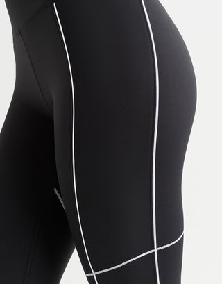 A woman wearing black leggings with white piping.