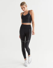 Woman wearing a black athletic outfit with white accents on a white background