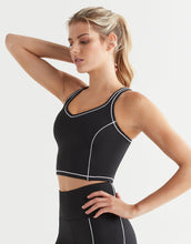 Woman wearing a black athletic top with white trim on a light gray background