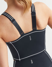 Black waist trainer with white accents on a person against a neutral background