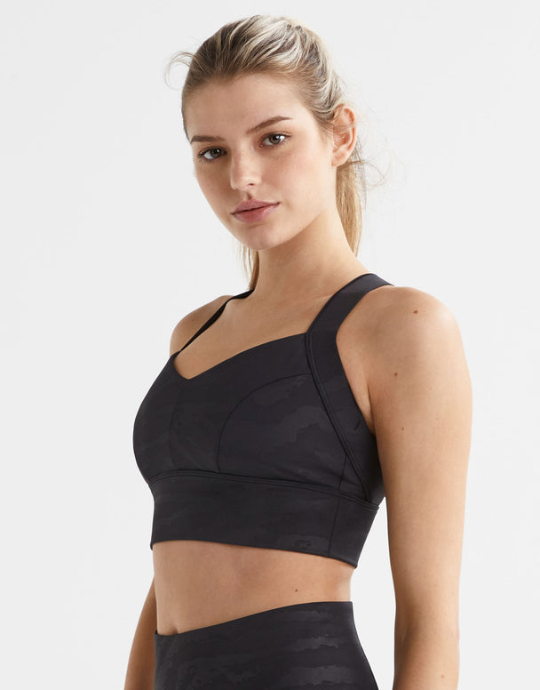 A woman wearing a black sports bra on a white background