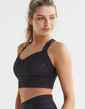 Woman wearing a black sports bra and leggings on a white background