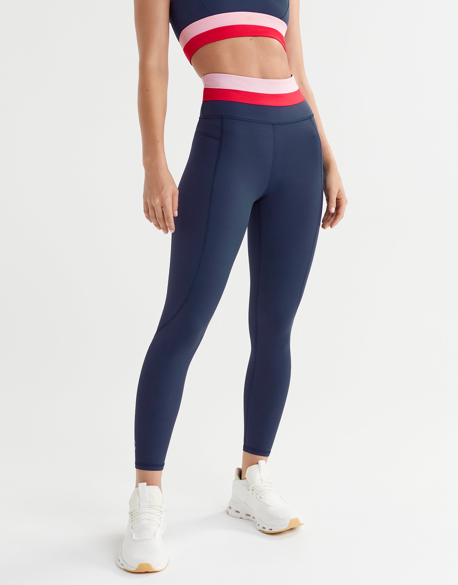 A woman wearing blue, red and pink leggings and a matching sports bra