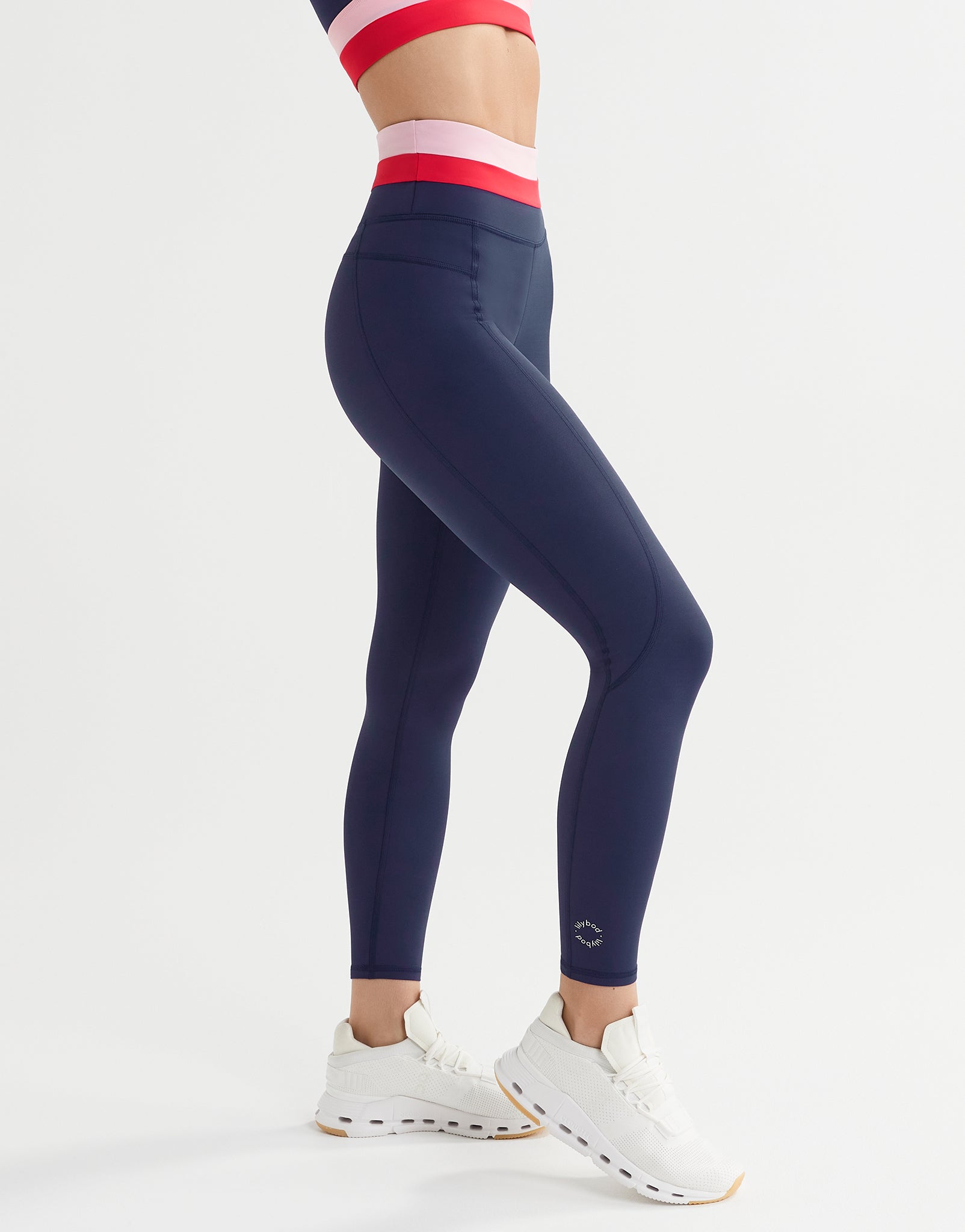 A woman wearing blue, red and pink leggings and white runners
