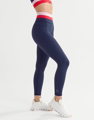 A woman wearing blue, red and pink leggings and white runners