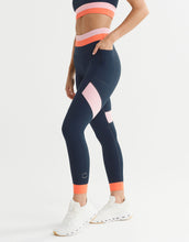 Person wearing navy leggings with pink and orange accents on a white background