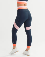 Person wearing navy leggings with pink accents on a white background