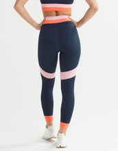 Navy leggings with pink and orange accents worn by a person on a white background