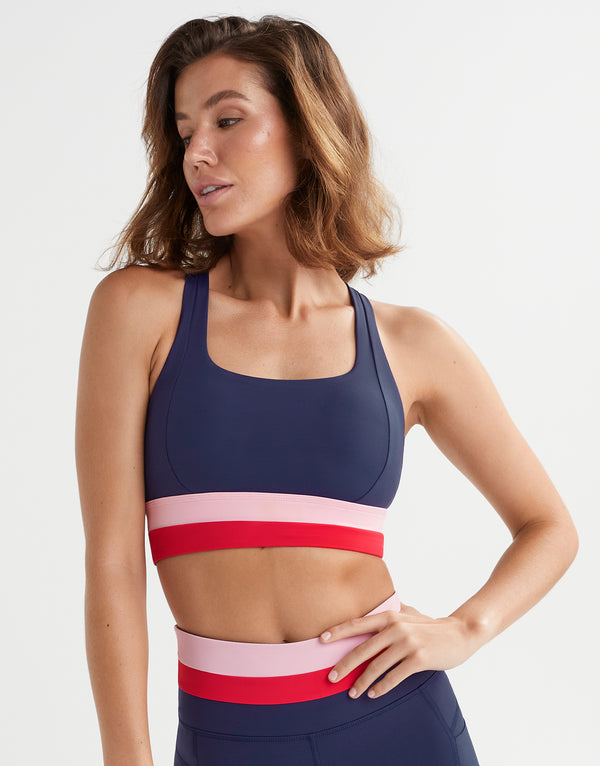 A woman wearing a navy, red and pink activewear set.