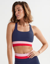 A woman wearing a navy, red and pink activewear set.