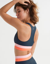 Woman wearing a sports bra with colorful straps on a white background