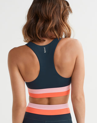 Navy sports bra with colorful stripes worn by a person on a white background
