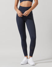 Person wearing navy blue leggings on a light gray background