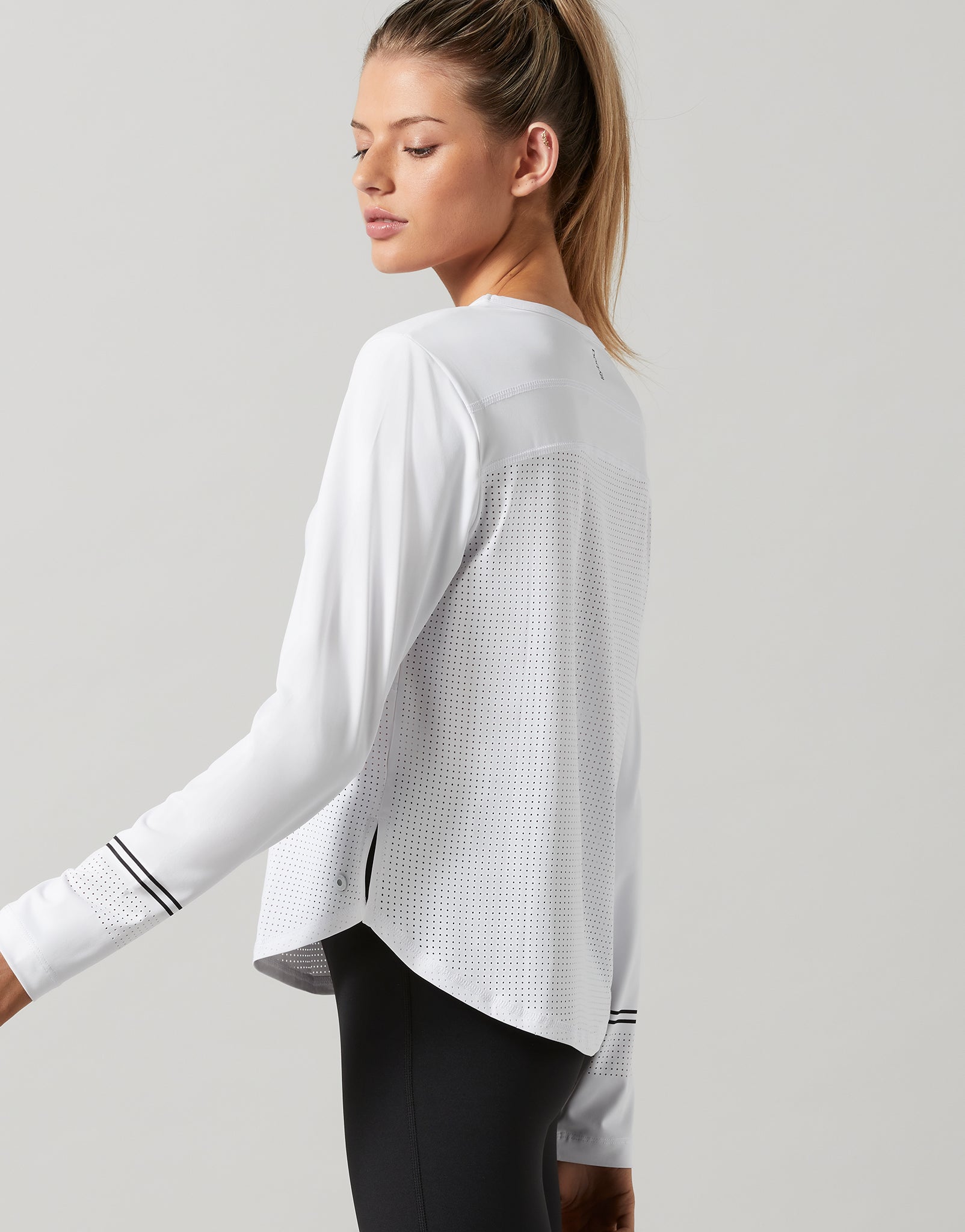 Woman wearing a white long-sleeve athletic top on a light gray background