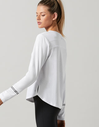 Woman wearing a white long-sleeve athletic top on a light gray background