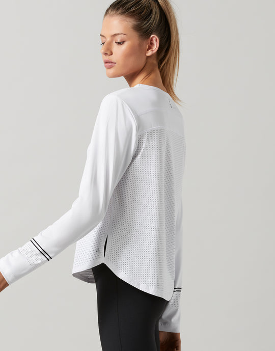 Woman wearing a white long-sleeve athletic top on a light gray background