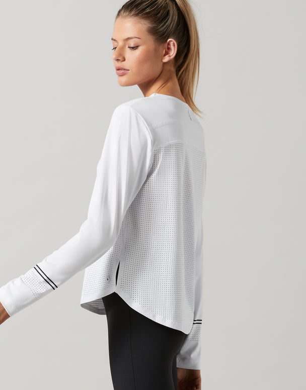 Woman wearing a white long-sleeve athletic top on a light gray background