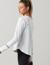 Woman wearing a white long-sleeve athletic top on a light gray background
