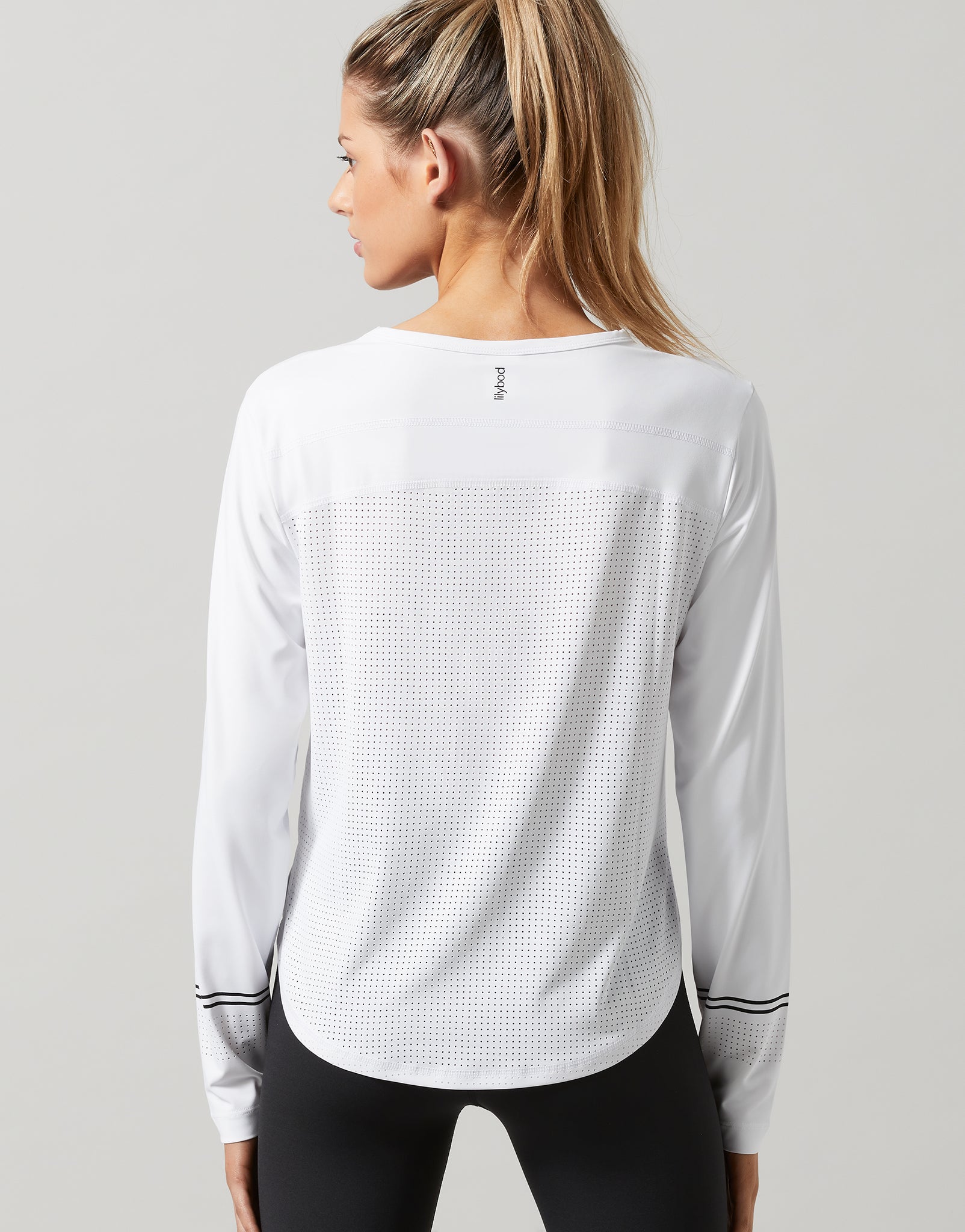 Woman wearing a white long-sleeve athletic shirt on a gray background