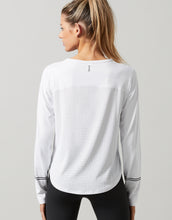 Woman wearing a white long-sleeve athletic shirt on a gray background