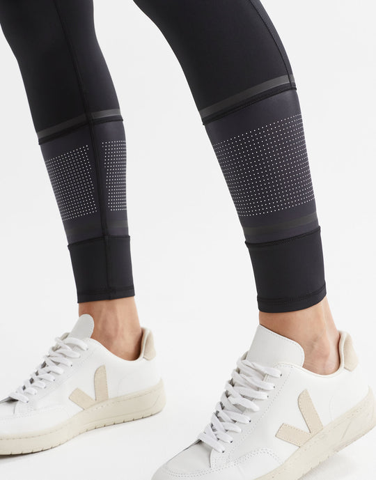 Black leggings with a white micro dot print and white sneakers.